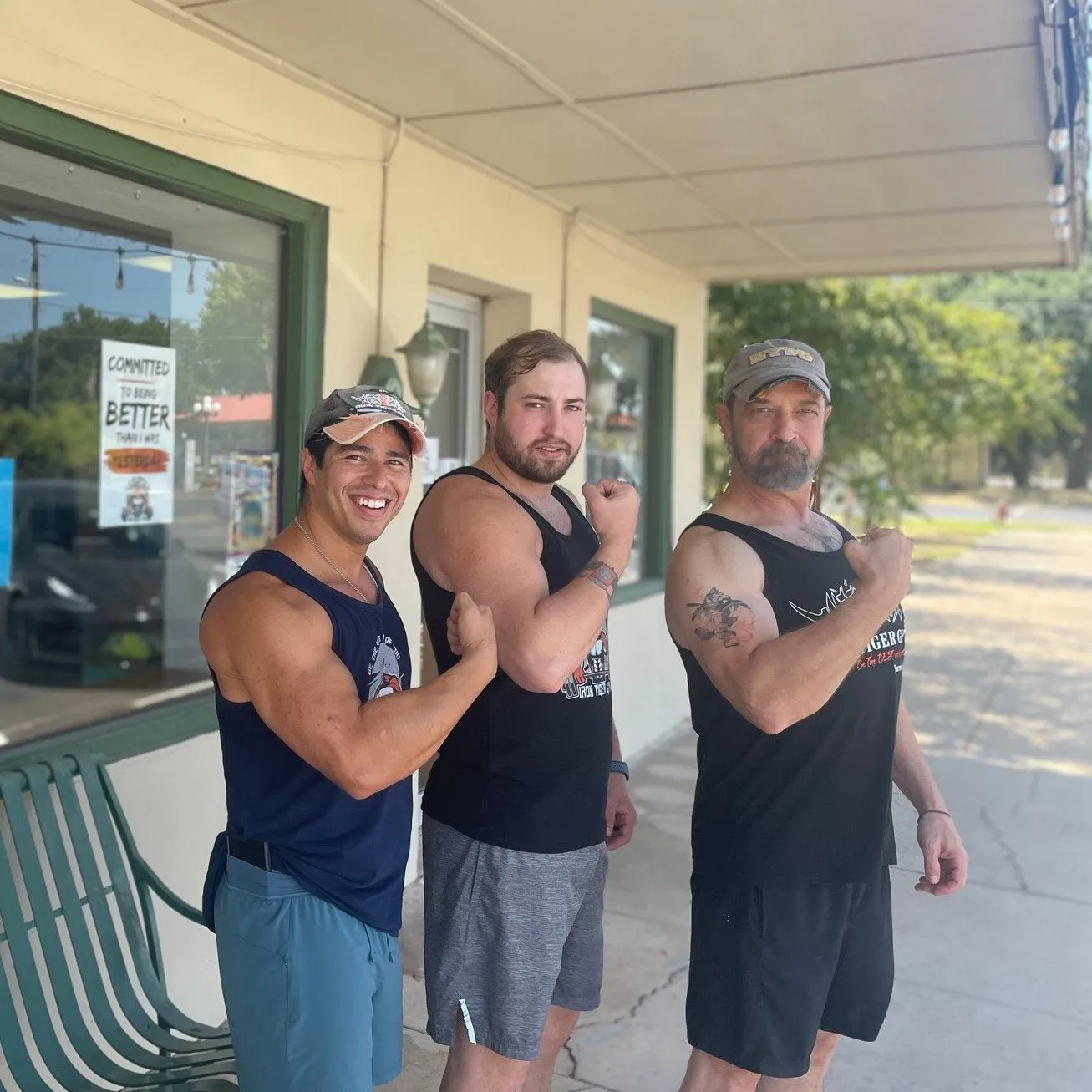 Three Iron Tiger members flexing on the sidewalk in front of the gym